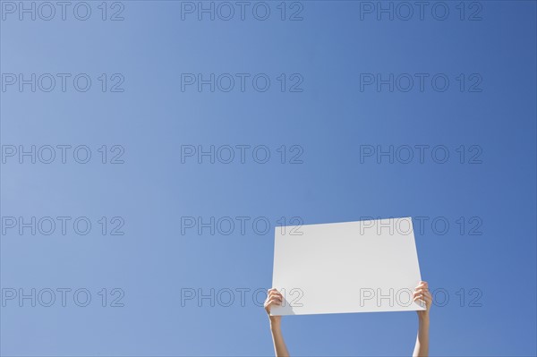 Arms holding a blank placard. Photo : Chris Hackett