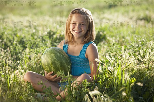 Young girl holding a watermelon. Photo : Mike Kemp