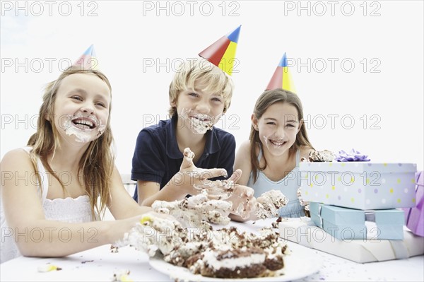 Children eating birthday cake with their hands. Photo. momentimages