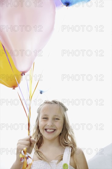 Young girl holding balloons. Photo : momentimages