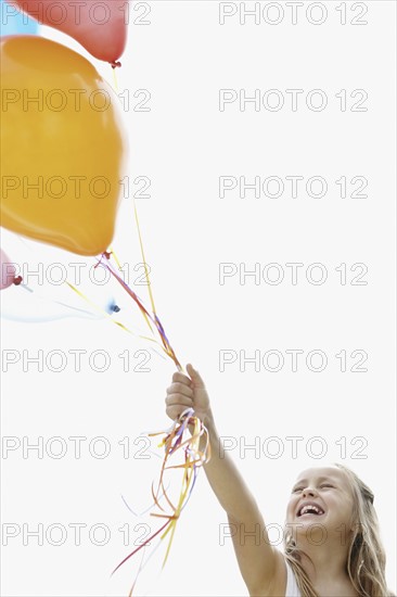 Young girl holding balloons. Photo : momentimages