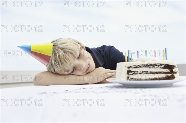 Young boy daydreaming about birthday cake. Photo. momentimages