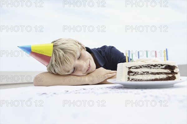 Young boy daydreaming about birthday cake. Photo : momentimages