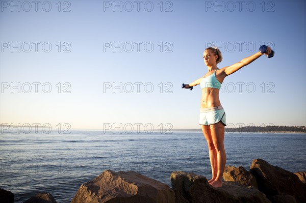 Athletic woman lifting weights outdoors. Photo : Take A Pix Media