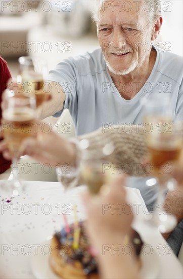 Senior man toasting with a glass of champagne. Photo : momentimages