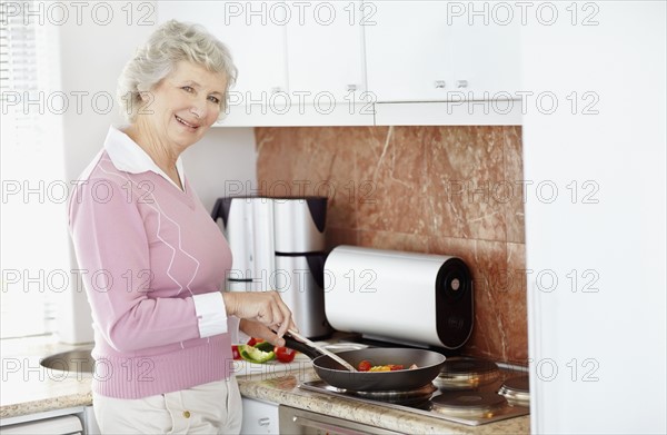 Senior woman cooking. Photo : momentimages