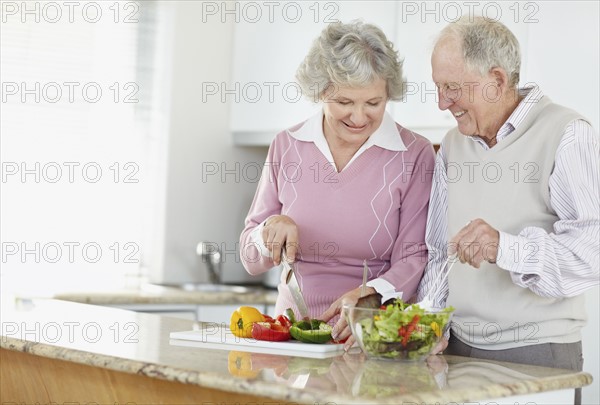 Senior couple preparing salad together. Photo. momentimages