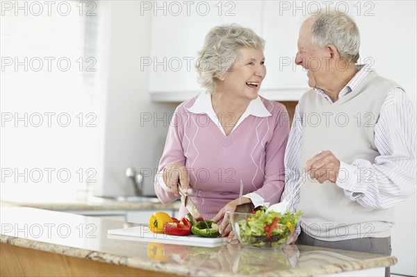 Senior couple preparing salad together. Photo : momentimages