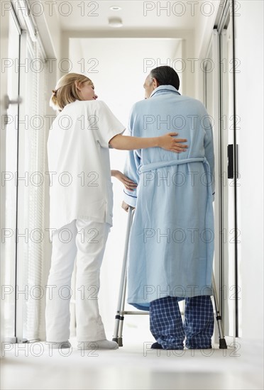 Nurse assisting patient with a walker. Photo. momentimages