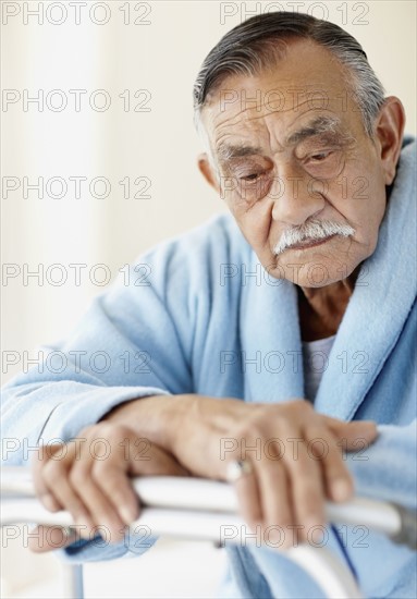 Elderly patient leaning on a walker. Photo. momentimages