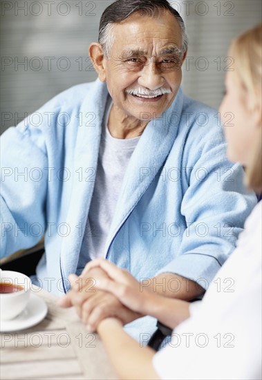 Nurse and senior patient sitting at table. Photo : momentimages