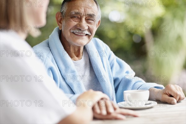 Senior man sitting at table with nurse. Photo. momentimages