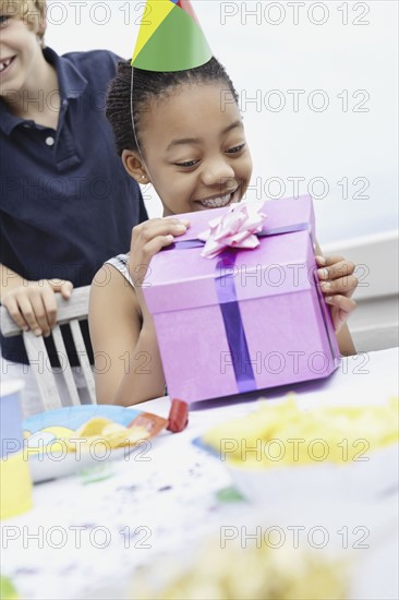 Young girl opening a birthday gift. Photo : momentimages