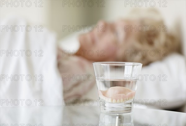 Dentures in a glass of water. Photo : momentimages