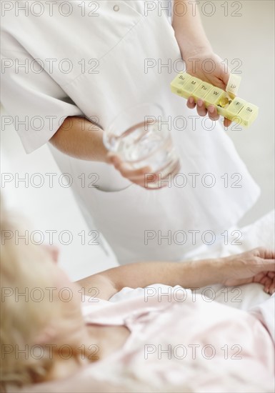 Nurse giving pill to senior woman. Photo. momentimages