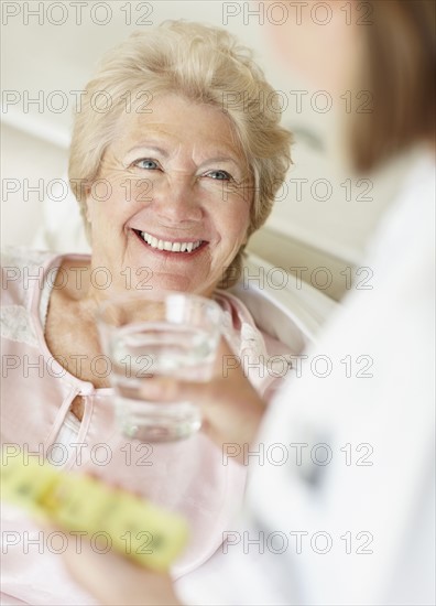 Nurse giving pill to senior woman. Photo : momentimages