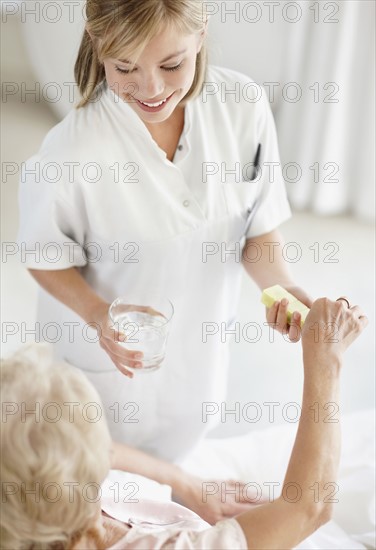 Nurse giving pill to senior woman. Photo. momentimages