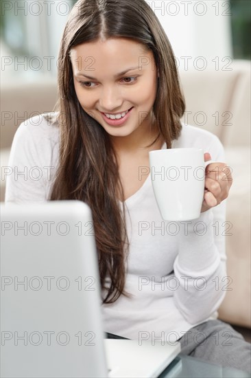 Woman drinking coffee while browsing the internet. Photo : momentimages