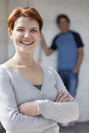 Cheerful woman standing with her arms crossed. Photo : momentimages