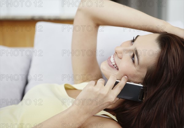 Smiling brunette woman talking on phone. Photo : momentimages