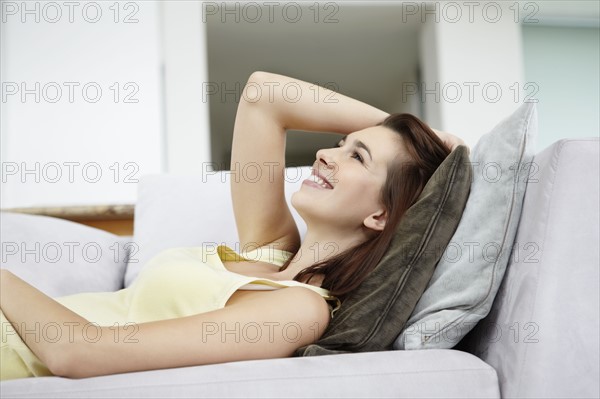 Cheerful brunette woman relaxing on couch. Photo. momentimages