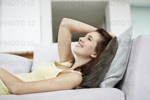 Cheerful brunette woman relaxing on couch. Photo : momentimages