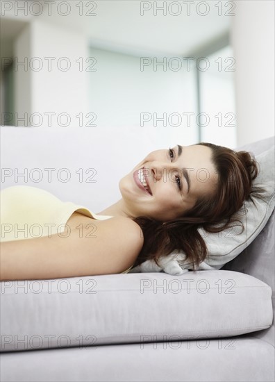 Cheerful brunette woman relaxing on couch. Photo : momentimages