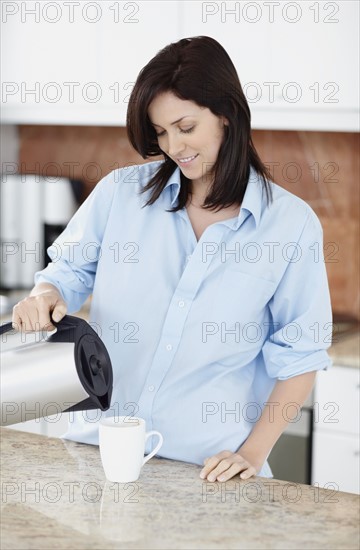 Brunette woman pouring coffee. Photo : momentimages