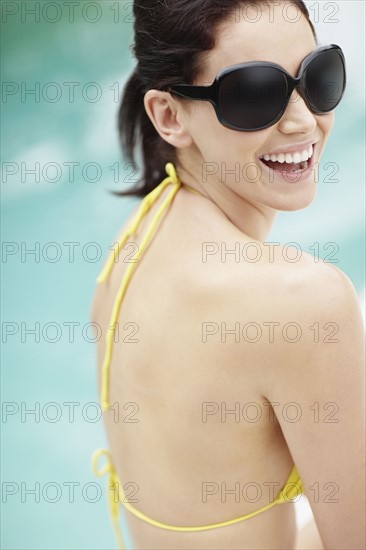 Laughing brunette wearing sunglasses and bikini. Photo : momentimages