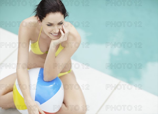 Attractive brunette sitting beside pool. Photo. momentimages