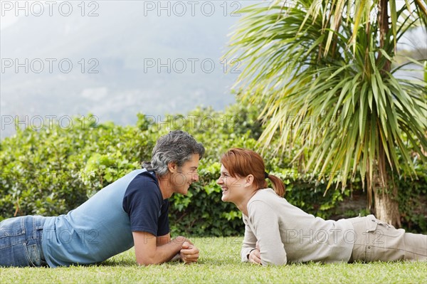 Happy couple lying face to face on the grass. Photo : momentimages