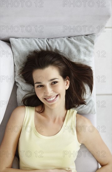 Cheerful brunette woman relaxing on couch. Photo : momentimages