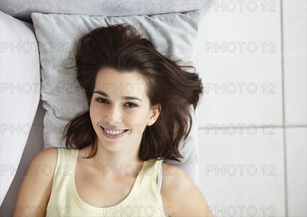 Cheerful brunette woman relaxing on couch. Photo : momentimages