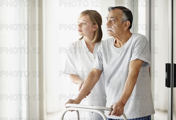 Nurse assisting patient with a walker. Photo. momentimages