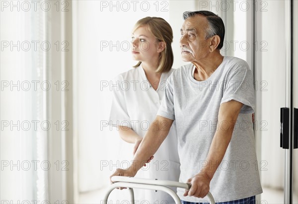 Nurse assisting patient with a walker. Photo : momentimages