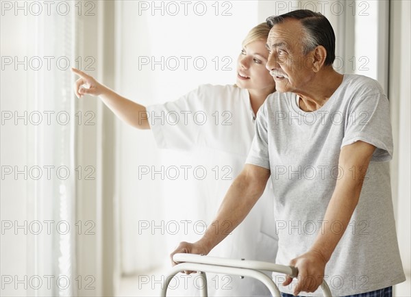 Nurse assisting patient with a walker. Photo : momentimages