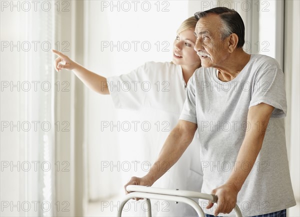 Nurse assisting patient with a walker. Photo. momentimages