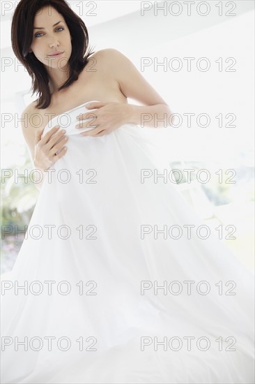 Sexy woman holding a bed sheet in front of her. Photo : momentimages