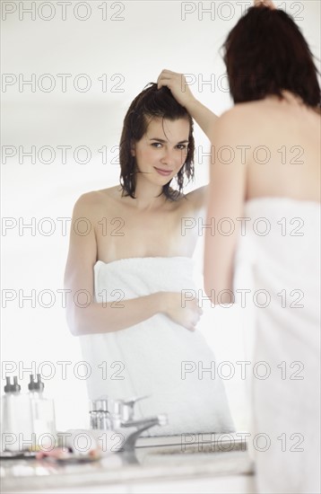 Woman looking at her reflection in mirror. Photo. momentimages