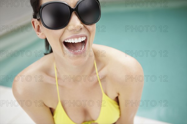 Laughing woman wearing bikini and sunglasses. Photo. momentimages