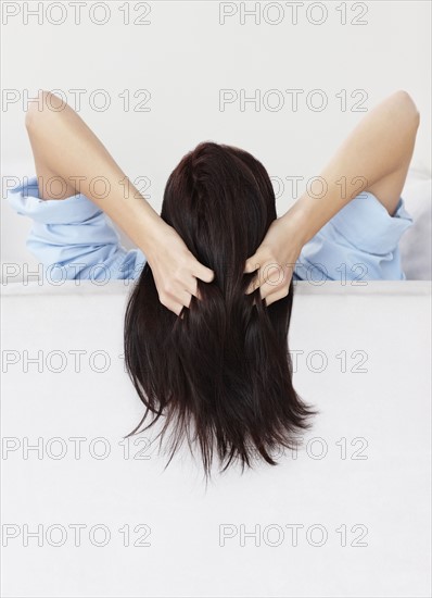 Brunette woman with her hands in her hair. Photo : momentimages