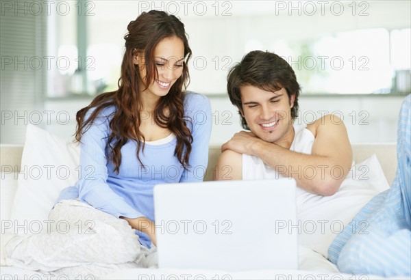 Couple looking at laptop together. Photo. momentimages