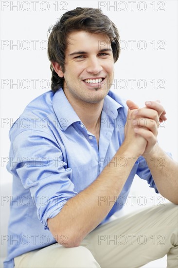 Handsome man sitting with hands clasped. Photo : momentimages