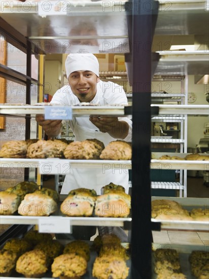 Baker standing behind trays of baked goods.