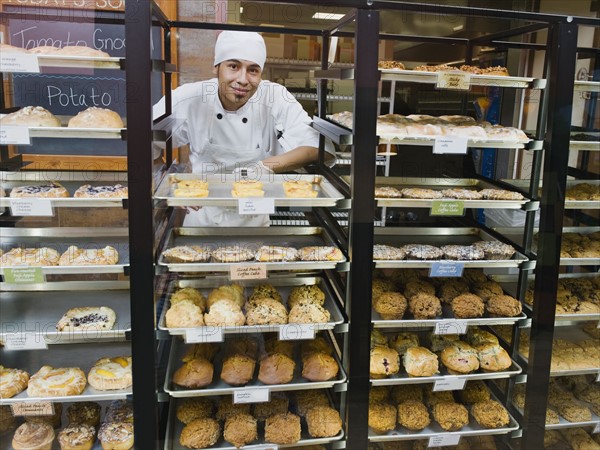 Baker standing behind trays of baked goods.