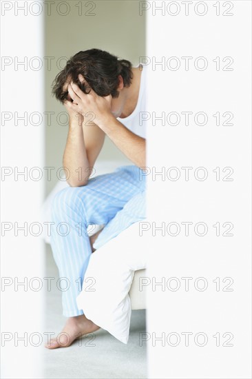 Frustrated man holding his head in his hands. Photo. momentimages