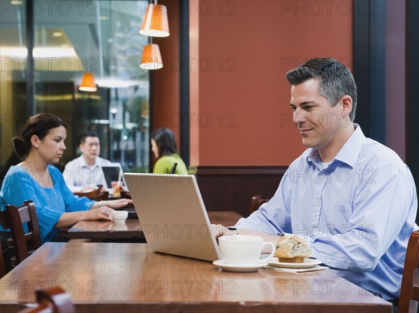 Man working on laptop in restaurant.