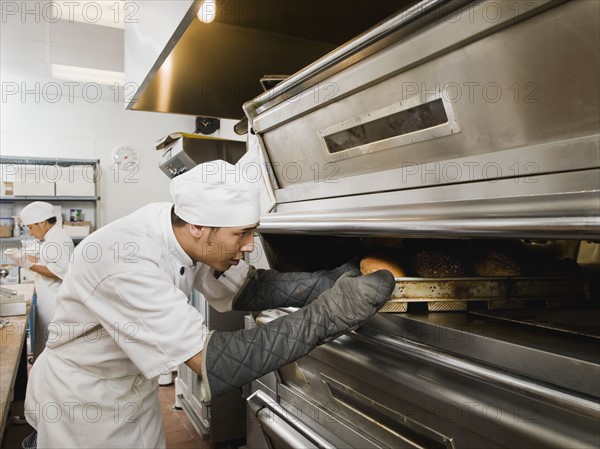 Chef putting bread in oven.