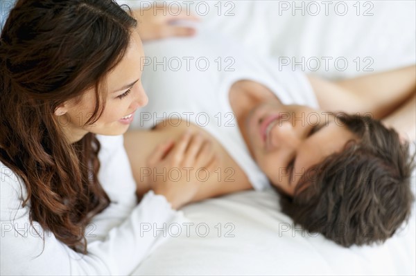 Couple relaxing on bed together. Photo : momentimages