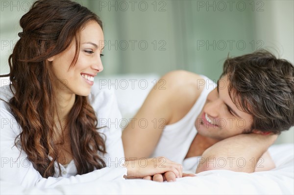 Couple relaxing on bed together. Photo. momentimages